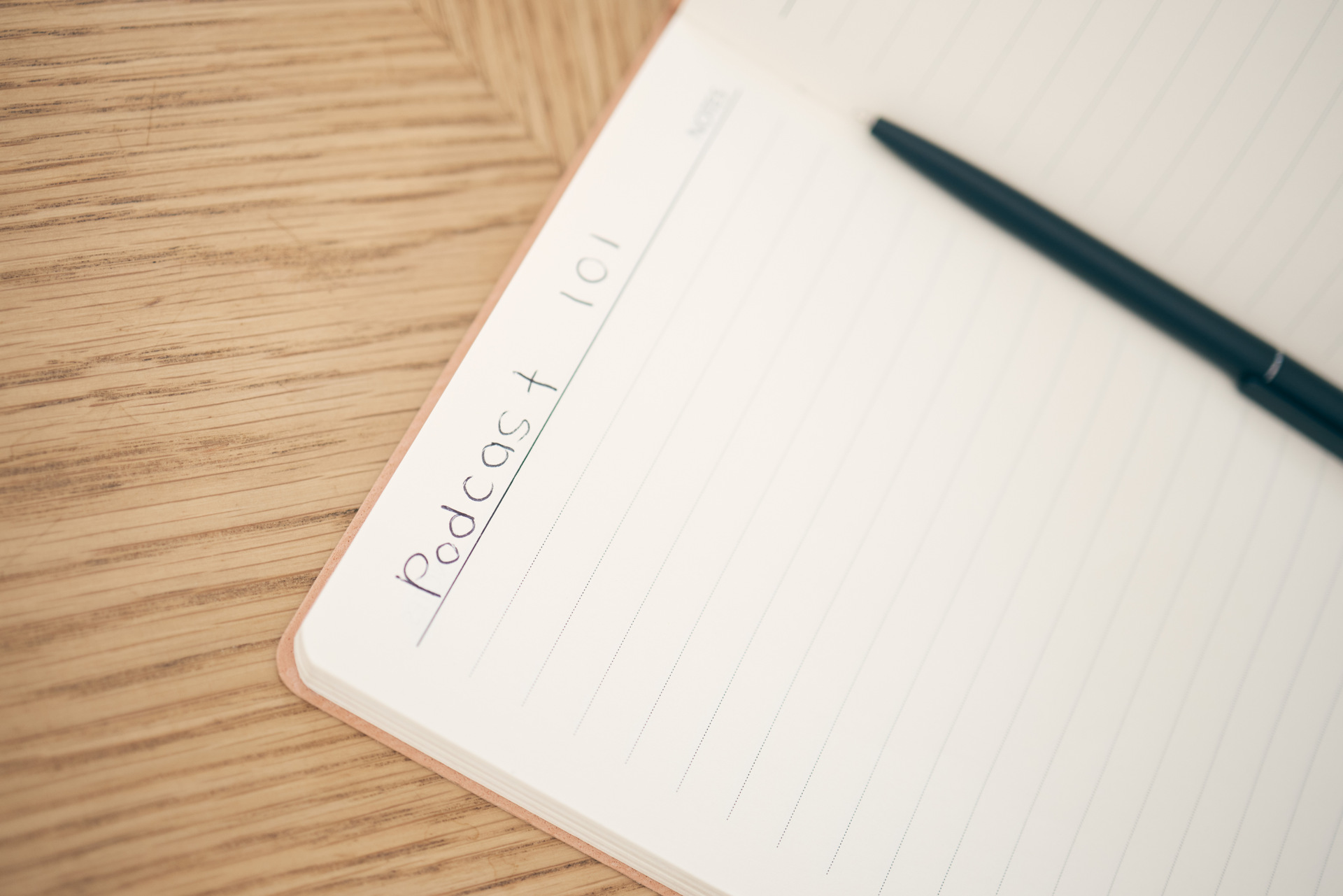 Notebook labeled Podcast 101 with pen, representing a strategic podcast launch plan